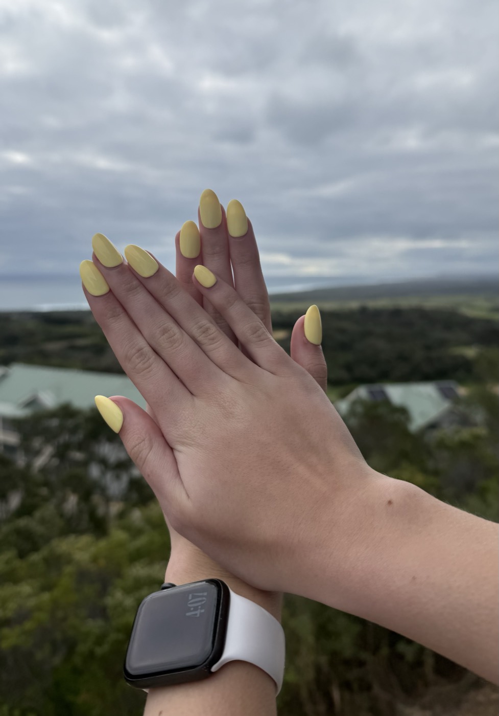 Hands wearing yellow almond-shaped press-on nails